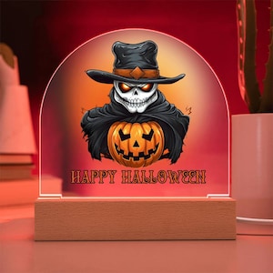 May include: A wooden base with a clear acrylic dome featuring a cartoon skull wearing a black hat and holding a jack-o-lantern. The text "Happy Halloween" is printed on the base.