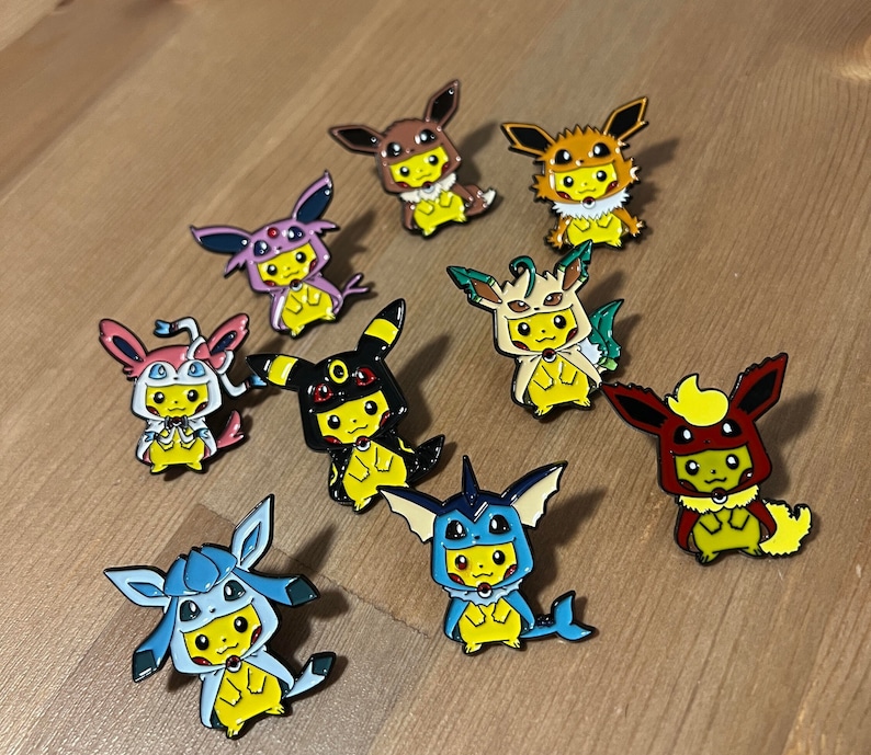 Pu&ograve; includere: Un set di dieci spille smaltate con diversi personaggi di Pok&eacute;mon. Le spille sono tutte in stile cartone animato e presentano i personaggi in varie pose. Le spille sono tutte di colori diversi e hanno una finitura lucida.