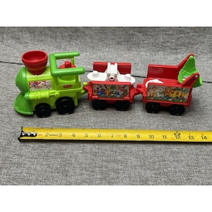 May include: A green and red toy train set with three cars. The train is approximately 13 inches long. The train cars have colorful illustrations of animals and other objects. The train is on a gray surface.