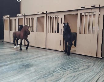 Op de afbeelding: Een digitaal lasergesneden bestand voor een miniatuur paardenstal met drie boxen. Het bestand is beschikbaar in de formaten SVG, DXF en Lightburn. De afbeelding toont een model van de stal met twee speelgoedpaarden die ervoor staan.