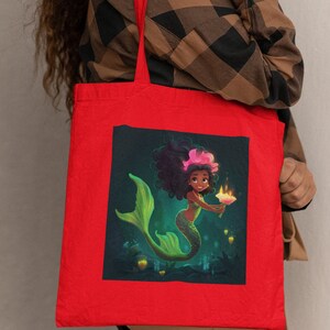 May include: Red tote bag with a graphic of a mermaid with green hair and a tail holding a glowing flower. The mermaid is surrounded by glowing orbs.
