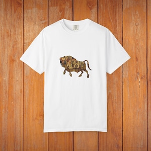 May include: A white t-shirt with a detailed illustration of a bison. The bison design is filled with a patterned design in shades of brown, tan, and gold. The shirt is made of a soft, comfortable material.