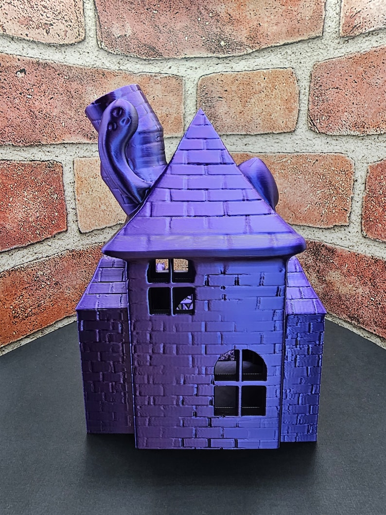 May include: A purple 3D printed house with a brick pattern and a whimsical, tentacled chimney. The house has two windows with black frames.