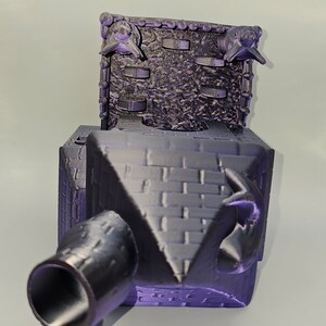 May include: A 3D printed purple model of a medieval castle with a cannon and gargoyles on the roof.