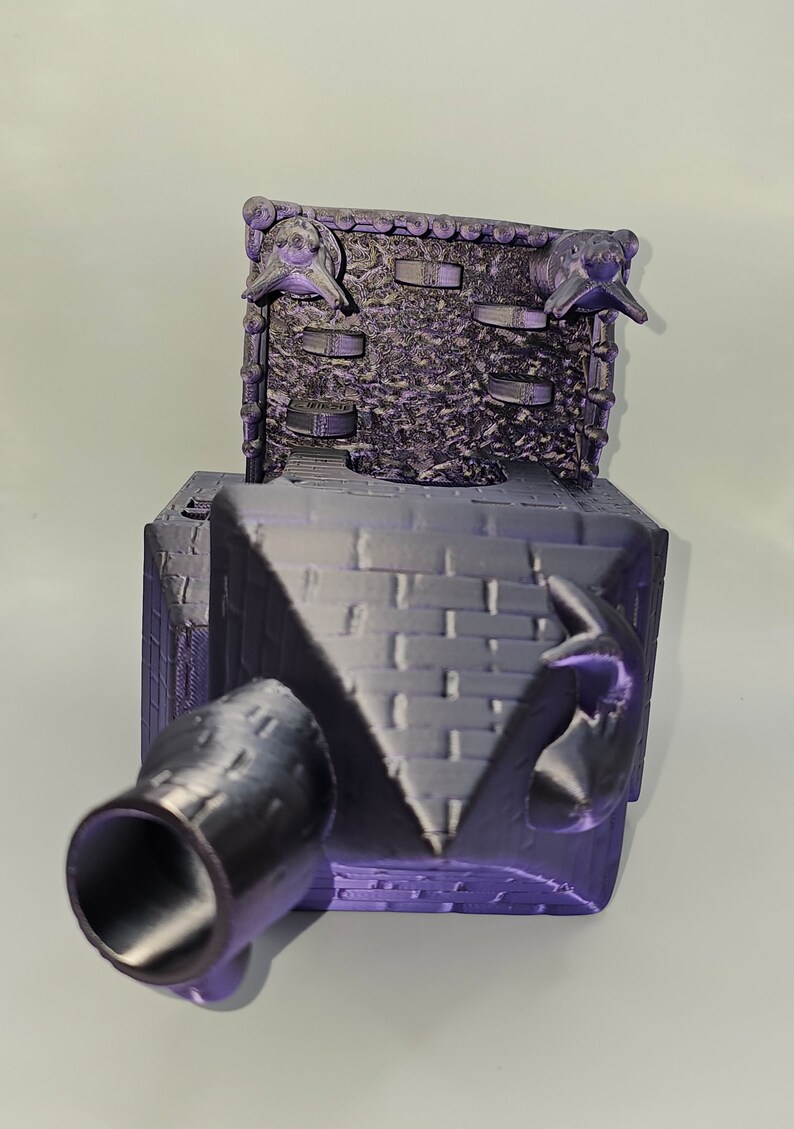 May include: A 3D printed purple model of a medieval castle with a cannon and gargoyles on the roof.