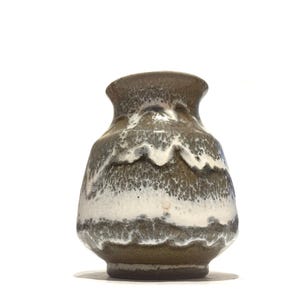 May include: A ceramic vase with a distinctive layered design. The vase showcases bands of white and dark brown glaze, giving it a textured, organic look. It has a rounded body and a slightly flared rim. The vase is suitable for displaying flowers or as a decorative item.