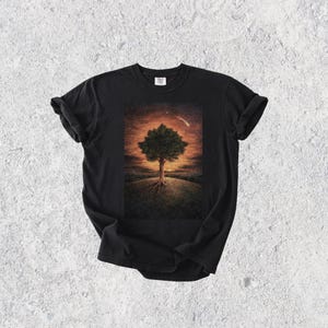 May include: Black t-shirt with a detailed illustration of a tree with exposed roots on a grassy hill, set against a sunset sky with a shooting star. The artwork is centered on the shirt.