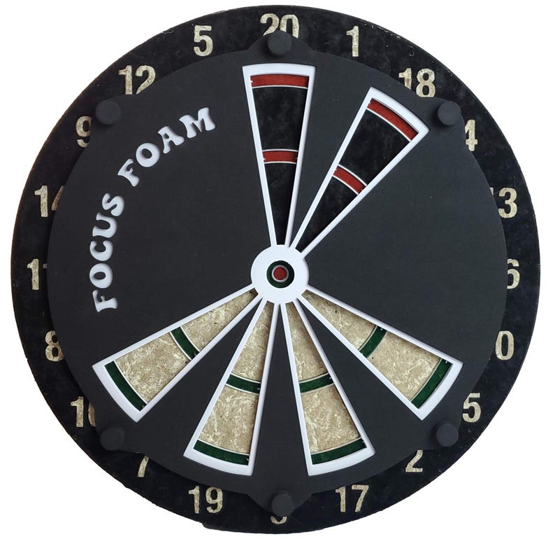 May include: A black dartboard with white numbers and a white and green bullseye. The dartboard has the words "FOCUS FOAM" printed on it in white.