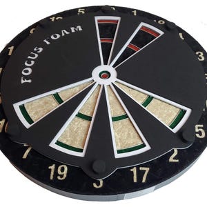 May include: A black dartboard with a white and green bullseye and the text "FOCUS FOAM" printed on the top. The numbers 1 through 20 are printed around the edge of the board.
