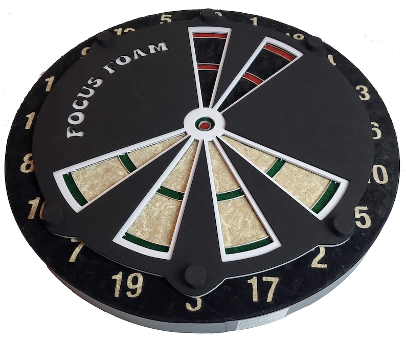 May include: A black dartboard with a white and green bullseye and the text "FOCUS FOAM" printed on the top. The numbers 1 through 20 are printed around the edge of the board.