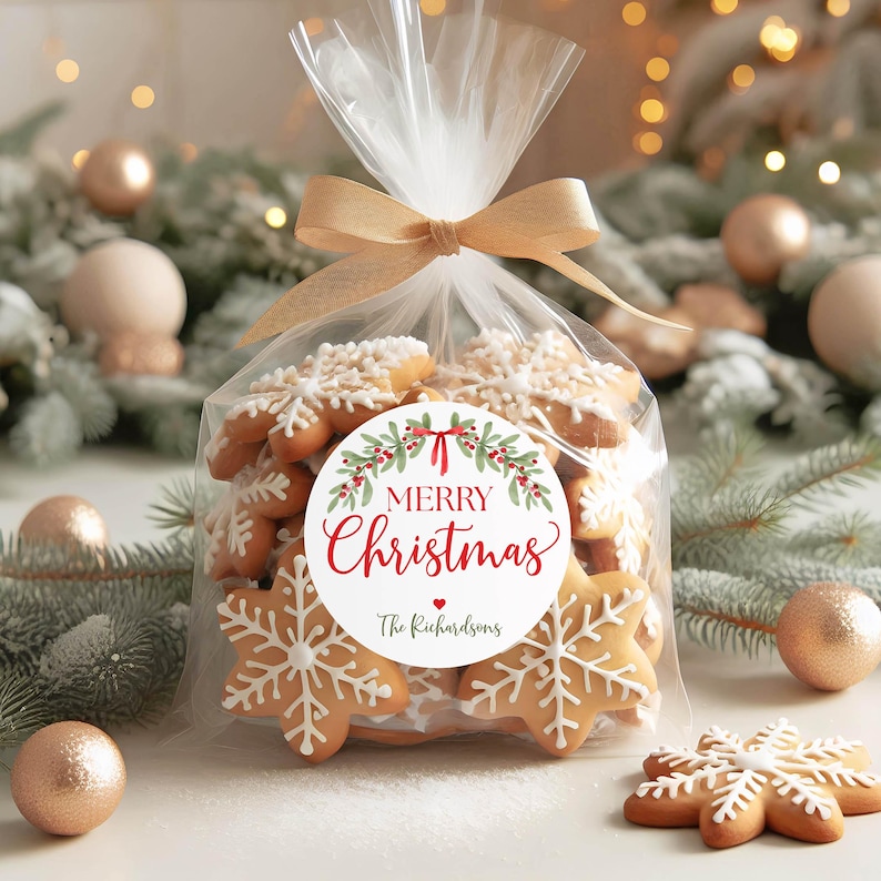May include: A clear cellophane bag filled with snowflake-shaped gingerbread cookies, tied with a gold ribbon. A round white label on the front features a green holly wreath, red berries, and the text Merry Christmas and The Richardsons.