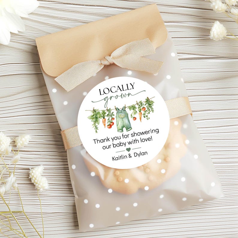 May include: A cellophane bag with a beige bow and a round sticker that reads "Locally Grown." The sticker features a watercolor illustration of vegetables and overalls. The text on the sticker says, "Thank you for showering our baby with love!" and the names Kaitlin & Dylan.
