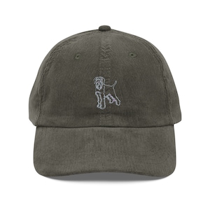 May include: A green corduroy baseball cap with an embroidered image of a black and white dog.