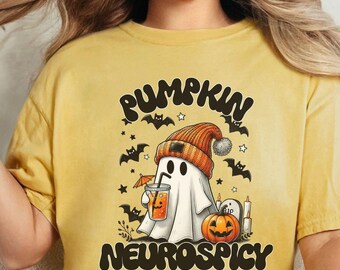 May include: A yellow t-shirt with a graphic of a ghost wearing a pumpkin hat and holding a pumpkin spice drink. The text "Pumpkin Neurospicy" is printed on the shirt.
