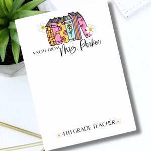 May include: A white notepad with a stack of colorful books and flowers. The text "A note from Mrs. Parker 4th Grade Teacher" is printed on the notepad.