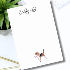 May include: White notepad with the name "Emily West" written in black cursive at the top. A cartoon beagle dog with a pink bow is printed in the bottom right corner.
