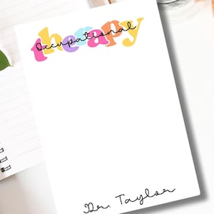 May include: White notepad with the text "Occupational Therapy" in colorful, stylized letters. The notepad has a black handwritten signature that says "Dr. Taylor".