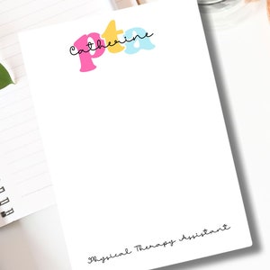 May include: A white notepad with the text "Catherine PTA" in colorful letters and the text "Physical Therapy Assistant" at the bottom.