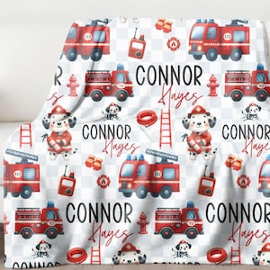 May include: White fleece blanket with a red, black, and blue fire truck, dalmatian dog, and fire hydrant pattern. The blanket has the name "CONNOR Hayes" repeated throughout the pattern.