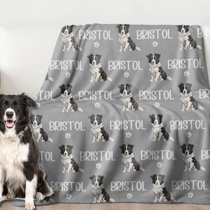 May include: A gray fleece blanket with a repeating pattern of black and white border collies. The blanket features the name "Bristol" printed on it.