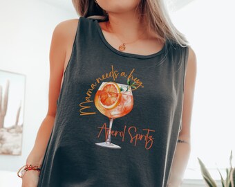 May include: A dark gray tank top with the text "Mama needs a hug Aperol Spritz" in orange and red lettering. The text is accompanied by a graphic of a glass of Aperol Spritz with an orange slice.
