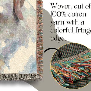 May include: Close-up of a woven cotton throw blanket with a colorful fringed edge. The blanket features a watercolor-style design with pastel colors. The text reads: "Woven out of 100% cotton yarn with a colorful fringed edge."