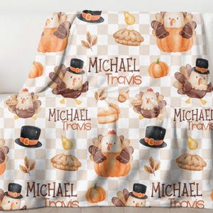 May include: Thanksgiving-themed blanket with a repeating pattern of cartoon turkeys wearing top hats, pumpkins, pie slices, and leaves on a checkered background. The blanket also features the text "MICHAEL Travis".