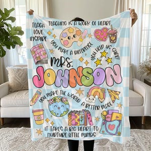 May include: A blue and white checkered blanket with a colorful design featuring the text "TEACHING IS A WORK OF HEART", "LOVE", "INSPIRE", "YOU MAKE A DIFFERENCE", "YOU HELP US GROW", "MRS. JOHNSON", "YOU MAKE THE WORLD A BETTER PLACE", and "IT TAKES A BIG HEART TO NURTURE LITTLE MINDS".