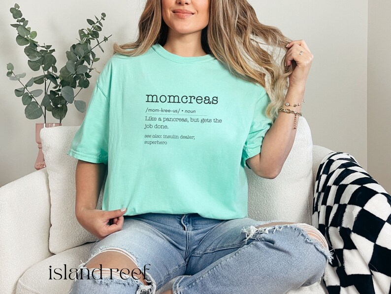 May include: A light blue t-shirt with the text "momcreas /mom-kree-us/ noun Like a pancreas, but gets the job done. see also insulin dealer, superhero" printed on the front.
