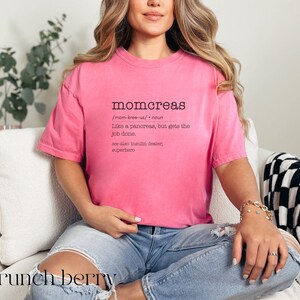 May include: A pink t-shirt with a humorous definition of "momcreas" printed on the front. The definition reads: "Like a pancreas, but gets the job done. See also insulin dealer, superhero."