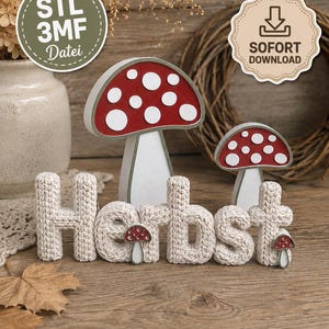 Könnte beinhalten: Ein dekoratives Arrangement mit dem Wort Herbst in beiger Häkeloptik, ergänzt durch zwei größere rot-weiße Pilzfiguren und zwei kleinere rot-weiße Pilzakzente an den Buchstaben, inklusive Hinweisen zum digitalen Download als STL-Datei.