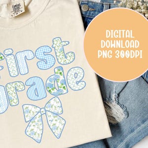 May include: A cream-coloured t-shirt featuring the words "first grade" in blue floral and patterned letters and a matching bow. The shirt is displayed on a denim background with a digital download graphic.