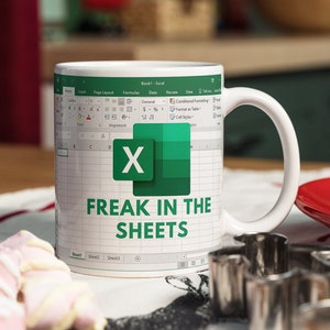 White ceramic 11oz Freak In The Sheets Excel mug with a graphic showing an Excel spreadsheet and the words Freak in the sheets. Perfect funny gift for a coworker, boss and friend.