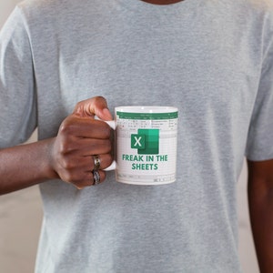 White ceramic 11oz Freak In The Sheets Excel mug with a graphic showing an Excel spreadsheet and the words Freak in the sheets. Perfect funny gift for a coworker, boss and friend.