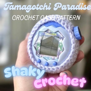 Könnte beinhalten: Eine hellviolette Häkelhülle für ein rundes Tamagotchi-Gerät, dessen Bildschirm das Tamagotchi-Logo und ein winterliches Muster zeigt. Der Text Tamagotchi Paradise CROCHET CASE PATTERN und shaky crochet sind im Bild zu sehen.
