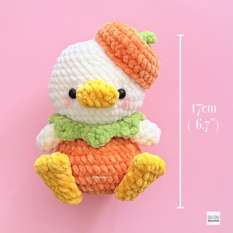 May include: A white crocheted plush duckling wearing an orange hat and orange body, featuring a green collar, yellow beak, and yellow feet. The plush toy measures 6.7 inches in height. It has black eyes and pink blush marks on its cheeks.
