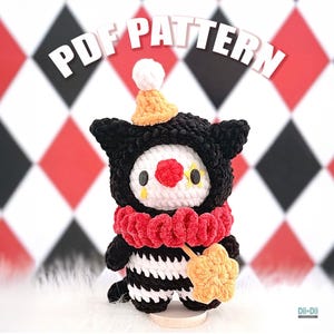 May include: A handmade crochet doll dressed as a clown. The doll features a black hood, a white face with a red nose, and yellow star-shaped eyes. It has a red ruffled collar and holds a yellow star. The text "PDF PATTERN" is above the doll.