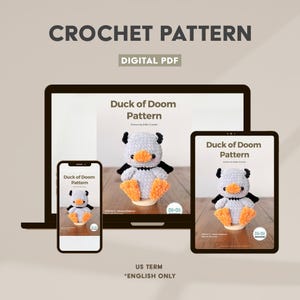 May include: A digital PDF crochet pattern titled Duck of Doom Pattern displayed on a laptop, tablet, and smartphone screen. The pattern features a light gray crocheted duck with black horns, black wings, and orange feet. Text includes US TERM *ENGLISH ONLY.