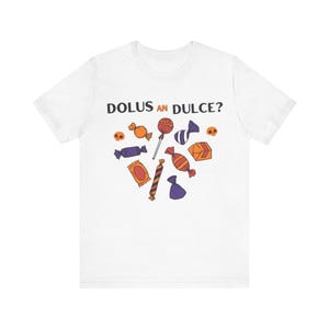 May include: White t-shirt with the text "Dolus an Dulce?" above a collection of colorful candy illustrations, including lollipops, wrapped candies, and small skulls. The candy is in shades of orange, purple, red, and yellow.