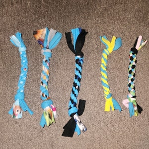 May include: Five colorful dog toys made of knotted fabric with different patterns. The toys are blue, yellow, black, and white.