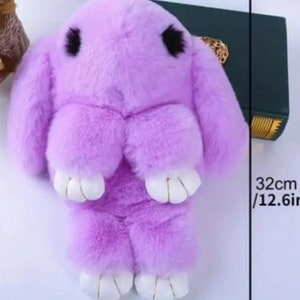 May include: A plush purple bunny keychain with white feet and black eyes. The keychain measures 12.6 inches tall and 7.09 inches wide.