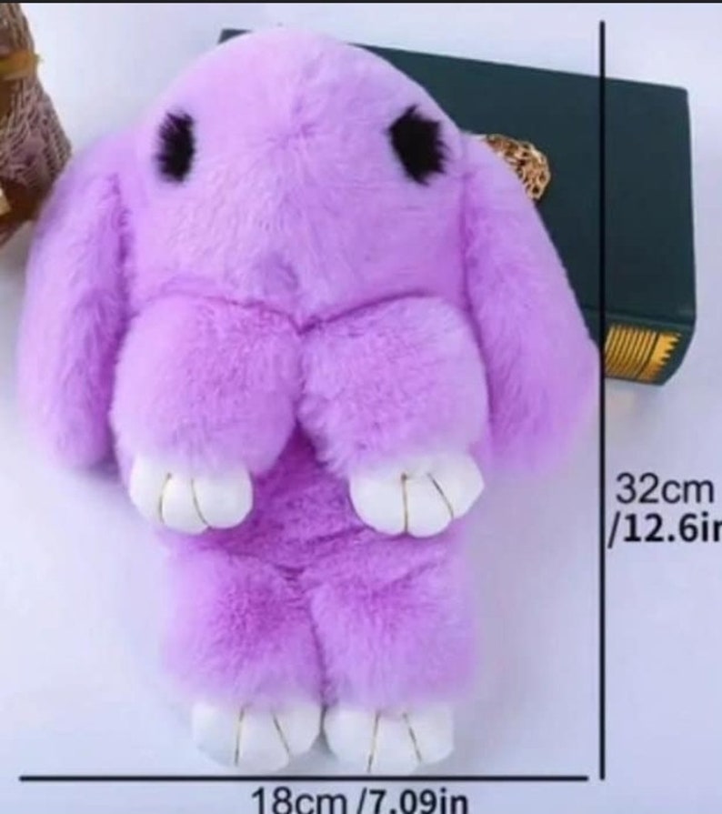 May include: A plush purple bunny keychain with white feet and black eyes. The keychain measures 12.6 inches tall and 7.09 inches wide.