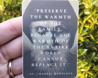 Puede incluir: Una pegatina con una cita de San Charbel Makhlouf: 'Preserva la calidez de la familia, porque la calidez del mundo entero no puede reemplazarla.'
