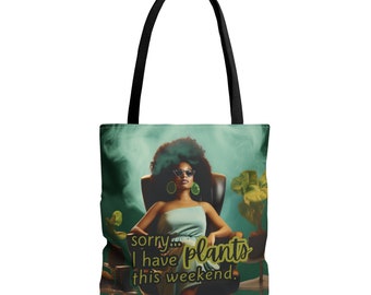 May include: A green tote bag with a black handle and a design featuring a woman with dark curly hair wearing sunglasses and a blue dress. The text on the bag reads "sorry... I have plants this weekend."