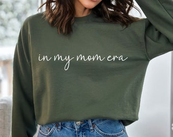 May include: A green sweatshirt with the text "in my mom era" in white lettering.