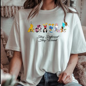 Camiseta "Stay Weird" con personajes de dibujos animados divertidos, camiseta gráfica "Stay Different", camiseta peculiar estilo Disney, regalo único para chicas raras DS63