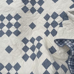 Puede incluir: Una colcha con estampado de rombos blancos y azules con un respaldo de cuadros azules y blancos.