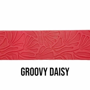 May include: A red silicone baking mat with a groovy daisy pattern. The mat is designed for use in the kitchen for baking and decorating.