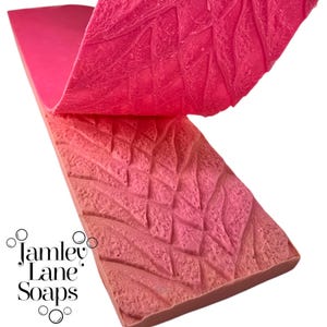 May include: A flexible, rectangular pink silicone soap mold featuring a textured, raised pattern of intersecting diagonal lines and organic shapes. The mold is partially folded back to reveal the detailed impression. The text Jamley Lane Soaps is visible.