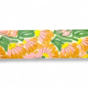May include: A bar of soap with a floral design. The soap is white with pink, orange, and green flowers.